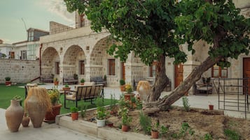 A courtyard with stone arches, outdoor seating, and potted plants.