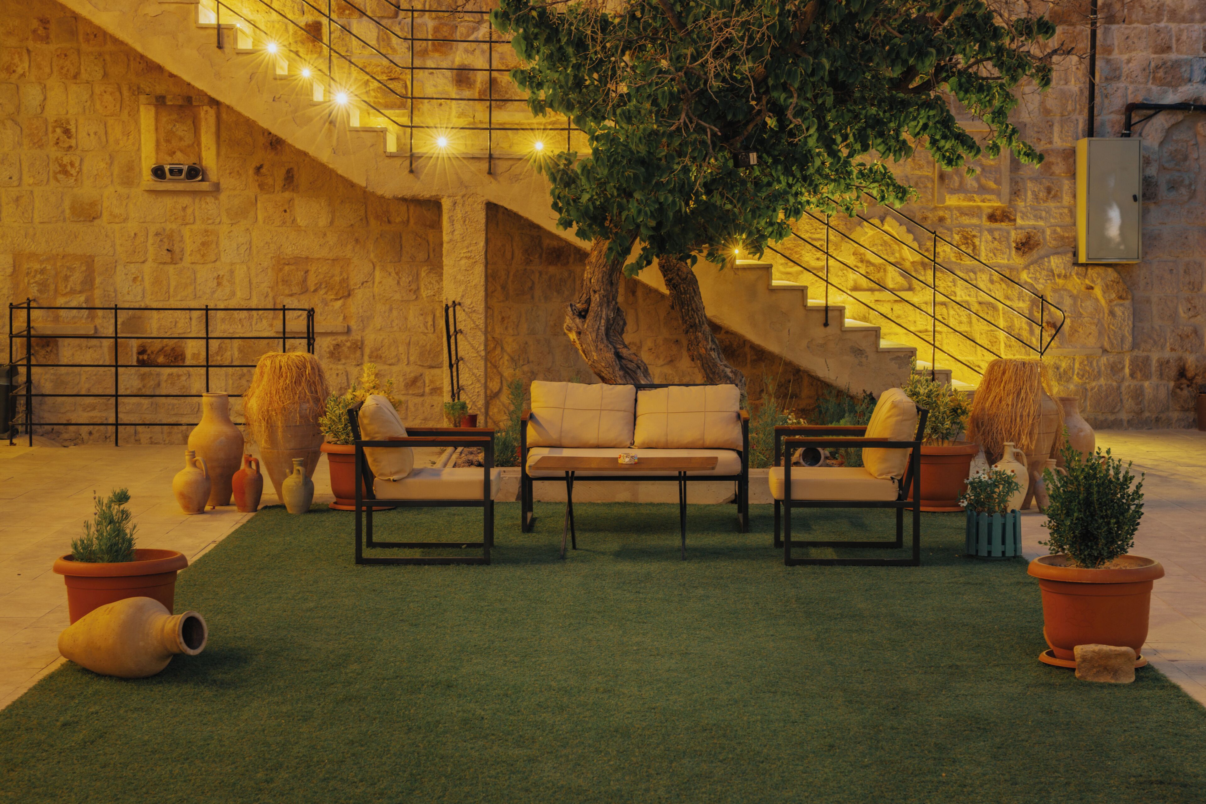 A courtyard with a staircase, a sofa set, and potted plants.