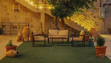 A courtyard with a staircase, a sofa set, and potted plants.