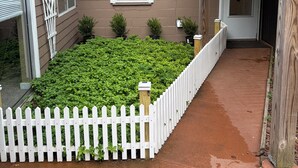 Een woonhuis met een witte picket fence, een kleine tuin en een deur die naar een garage leidt.