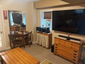 A compact living space with a dining table, chairs, a TV, a microwave, a coffee maker, and a dresser. - Serene 1-bedroom apartment with AC in East Hampton (East Hampton)