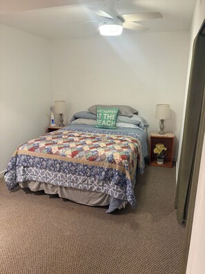 Une chambre à coucher comprenant un lit, deux lampes de chevet, une table de chevet, un ventilateur de plafond et une lampe fixée au mur.