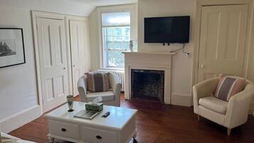 A living room with a fireplace, a television mounted above it, and two armchairs.