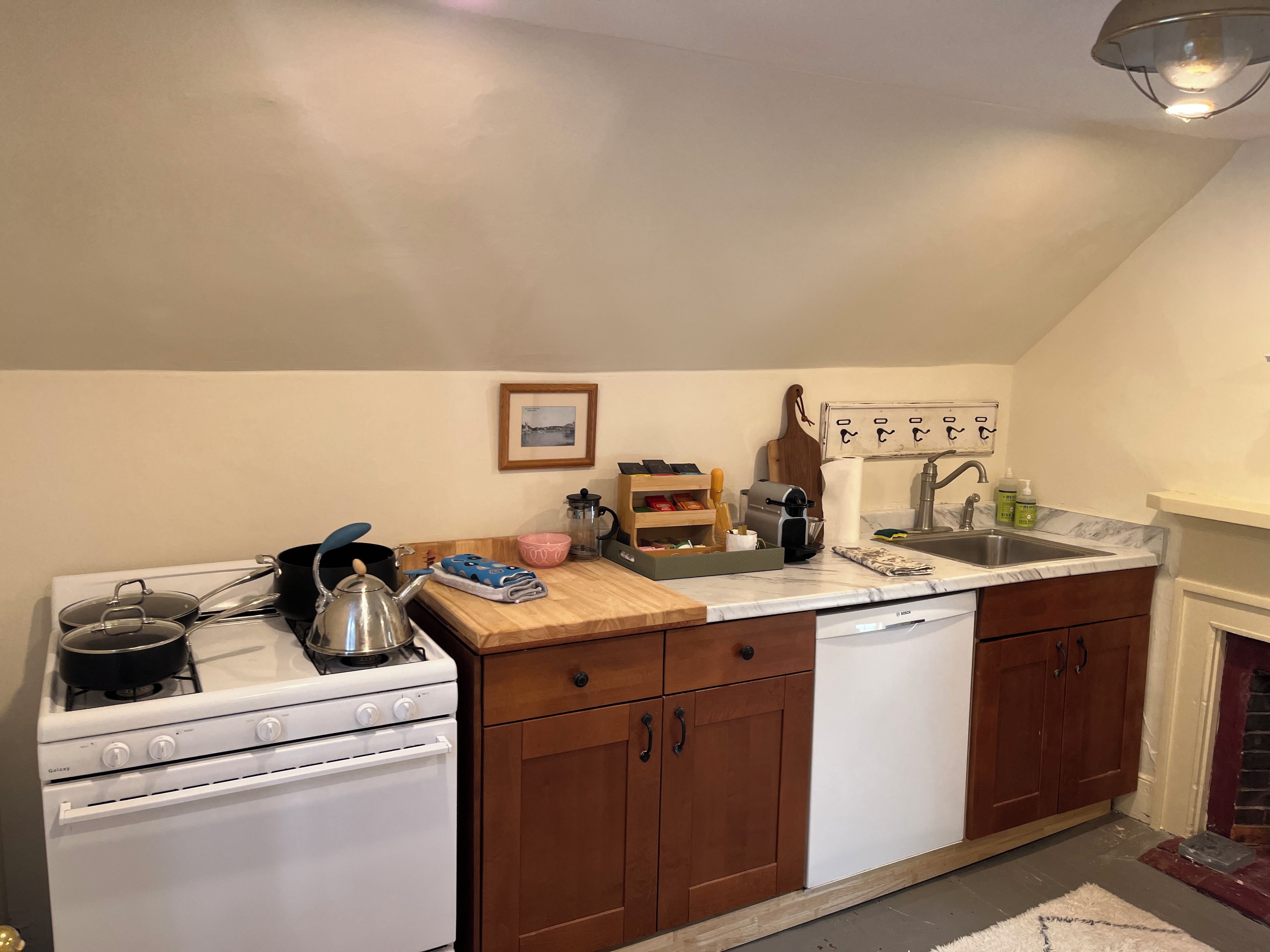 A kitchen with a gas stove, oven, wooden cabinets, a sink, and a marble countertop.