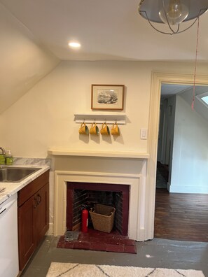 A kitchen with a white mantel, a framed picture, and a hanging light fixture.