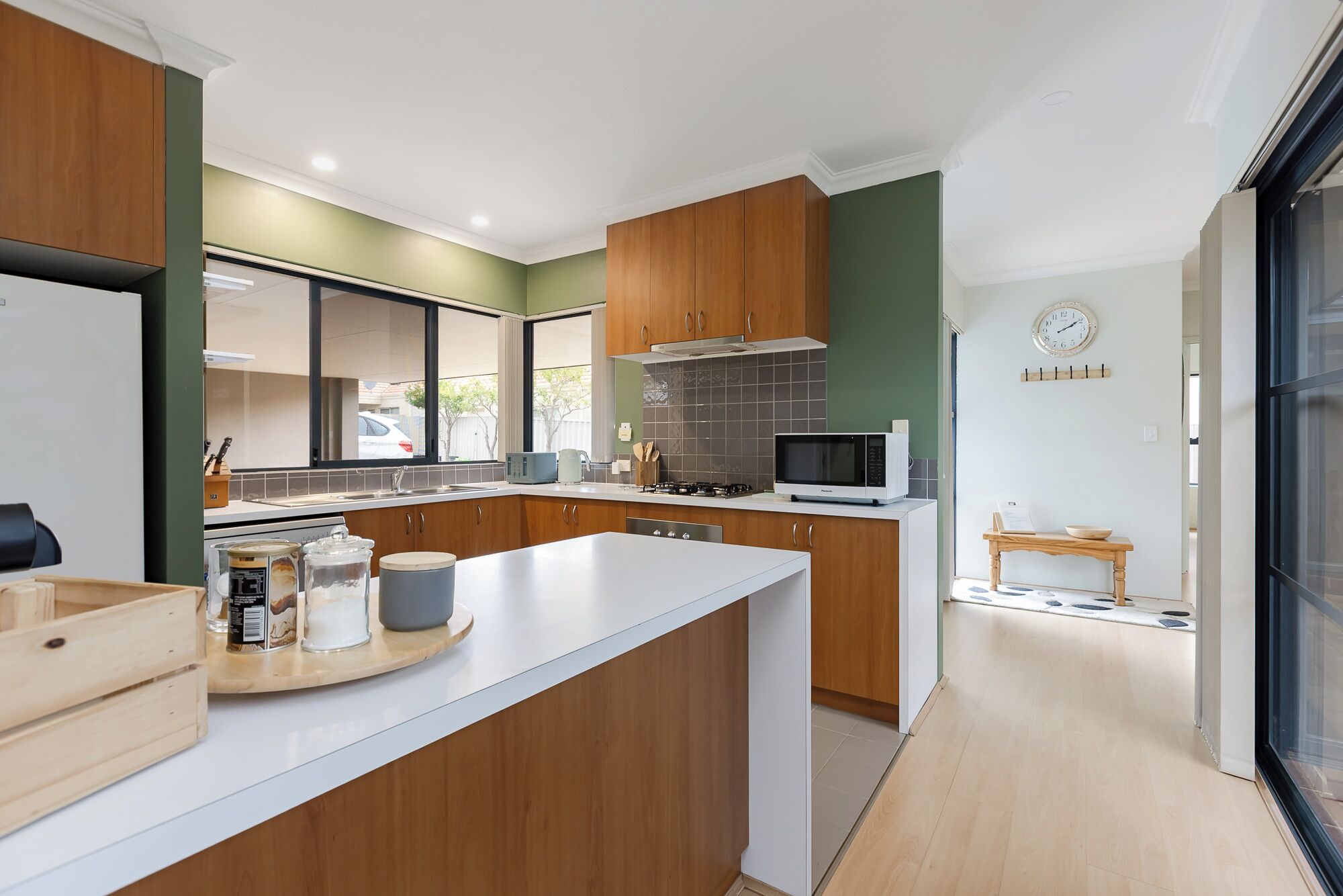 A modern kitchen with wooden cabinets, a central island, and a microwave.