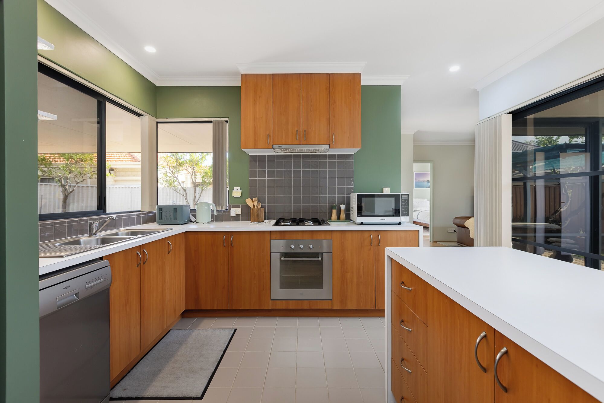 Une cuisine moderne avec des meubles en bois, un four encastré, un four à micro-ondes et un lave-vaisselle.