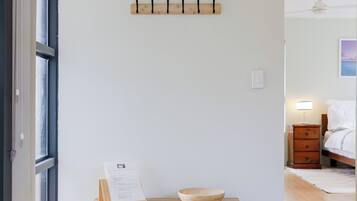 A hallway with a wooden bench, a wall-mounted clock, and a door leading to another room.