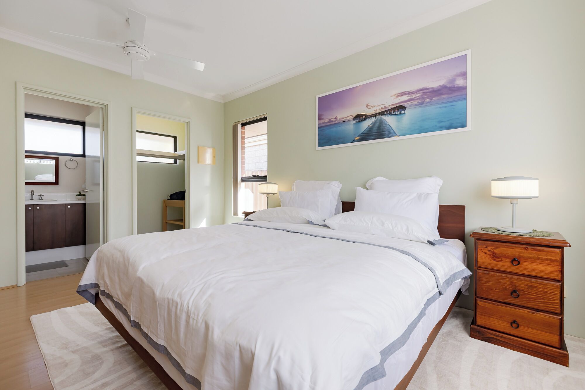 Une chambre à coucher avec un lit, une table de chevet et un tableau accroché au mur.