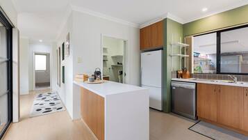 A modern kitchen with a central island, a refrigerator, a dishwasher, and wooden cabinets.