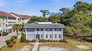 A two-story building with a flat roof, a central entrance, and a small front yard with a pathway leading to the entrance. - 4/2 bottom floor 1 block from beach (North Myrtle Beach)