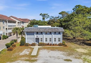 A two-story building with a flat roof, a central entrance, and a small front yard with a pathway leading to the entrance. - 4/2 bottom floor 1 block from beach (North Myrtle Beach)