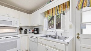 A compact kitchen with white cabinetry, a microwave, a coffee maker, and a sink. - 4/2 bottom floor 1 block from beach (North Myrtle Beach)