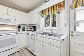 A compact kitchen with white cabinetry, a microwave, a coffee maker, and a sink. - 4/2 bottom floor 1 block from beach (North Myrtle Beach)