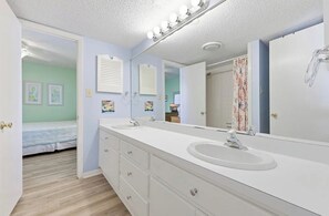A bathroom with a large mirror, two sinks, and a shower curtain. - 4/2 bottom floor 1 block from beach (North Myrtle Beach)