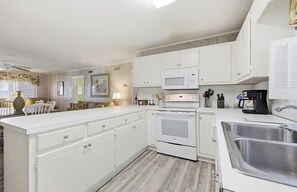 A kitchen with white cabinetry, a microwave, an oven, and a sink. - 4/2 bottom floor 1 block from beach (North Myrtle Beach)