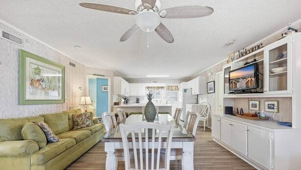A spacious living area with a dining table, a green sofa, and a ceiling fan. - 4/2 bottom floor 1 block from beach (North Myrtle Beach)