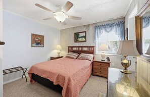 A bedroom with a bed, two bedside tables, a ceiling fan, a window with curtains, and a nightstand. - 8BR Beach House | Sleeps 20+ | Walk to Beach (North Myrtle Beach)