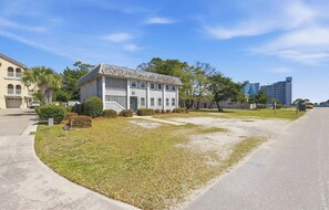 A two-story building with a front porch and a lawn in front. - 8BR Beach House | Sleeps 20+ | Walk to Beach (North Myrtle Beach)