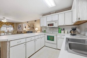A compact kitchen with white cabinets, a microwave, an oven, and a coffee maker. - 8BR Beach House | Sleeps 20+ | Walk to Beach (North Myrtle Beach)