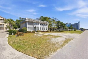 A two-story building with a front lawn and a driveway. - 8BR Beach House | Sleeps 20+ | Walk to Beach (North Myrtle Beach)