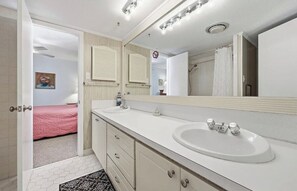Een badkamer met een wit wastafelmeubel, een spiegel en een douchecel.