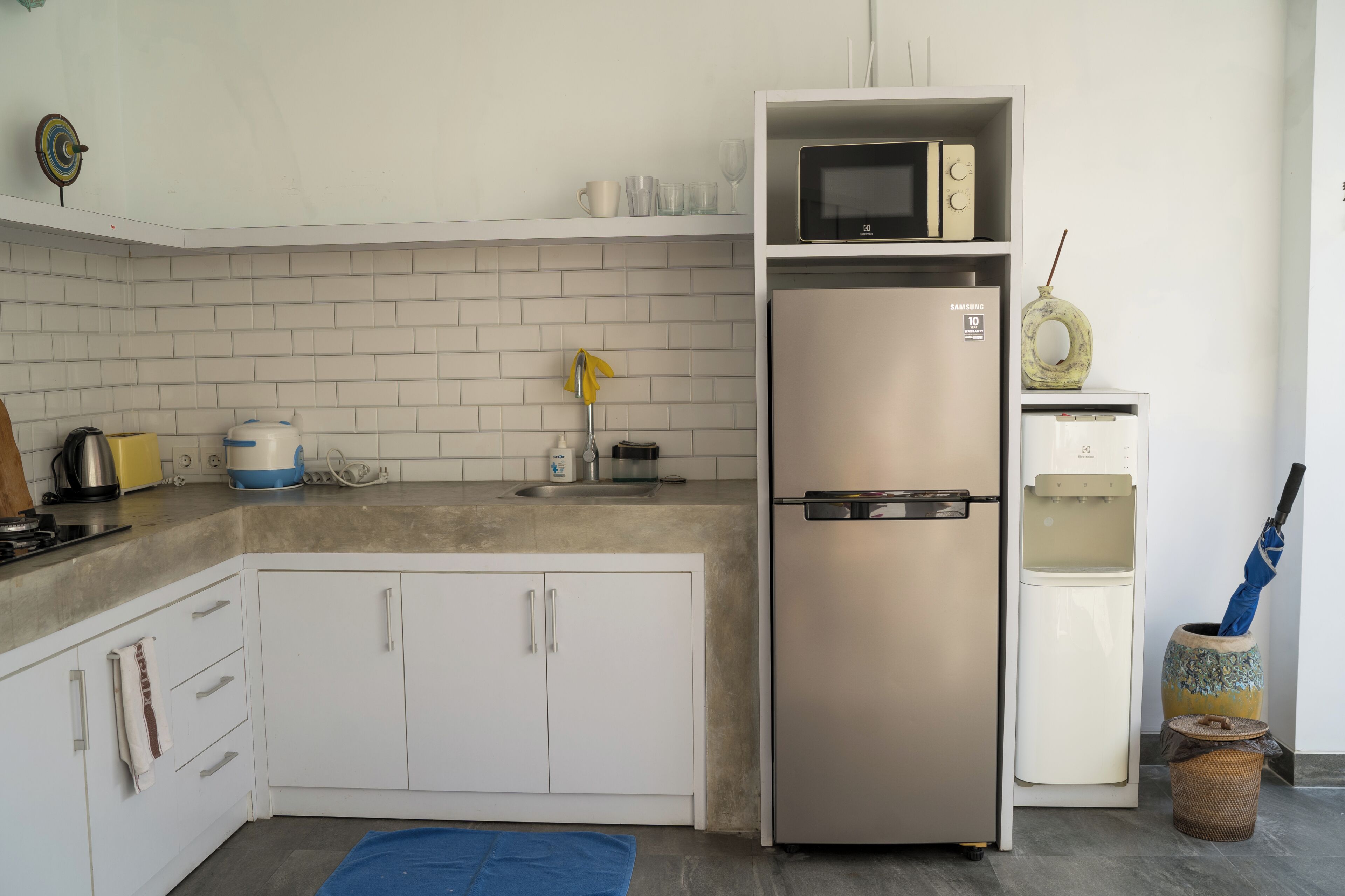 A compact kitchen with a stainless steel refrigerator, a microwave, and a sink.