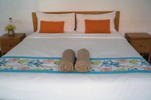 Een bed met twee kussens, een deken en twee opgerolde handdoeken.