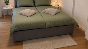 A bedroom with a bed, a bedside table, a lamp, a framed plant, and a carpet. - Modern Apartment • 200 m to the lake • Parking Lot Wi-Fi (Möhnesee)