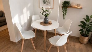 A dining area with a round table, four white chairs, a vase with flowers, and a hanging plant. - Modern Apartment • 200 m to the lake • Parking Lot Wi-Fi (Möhnesee)