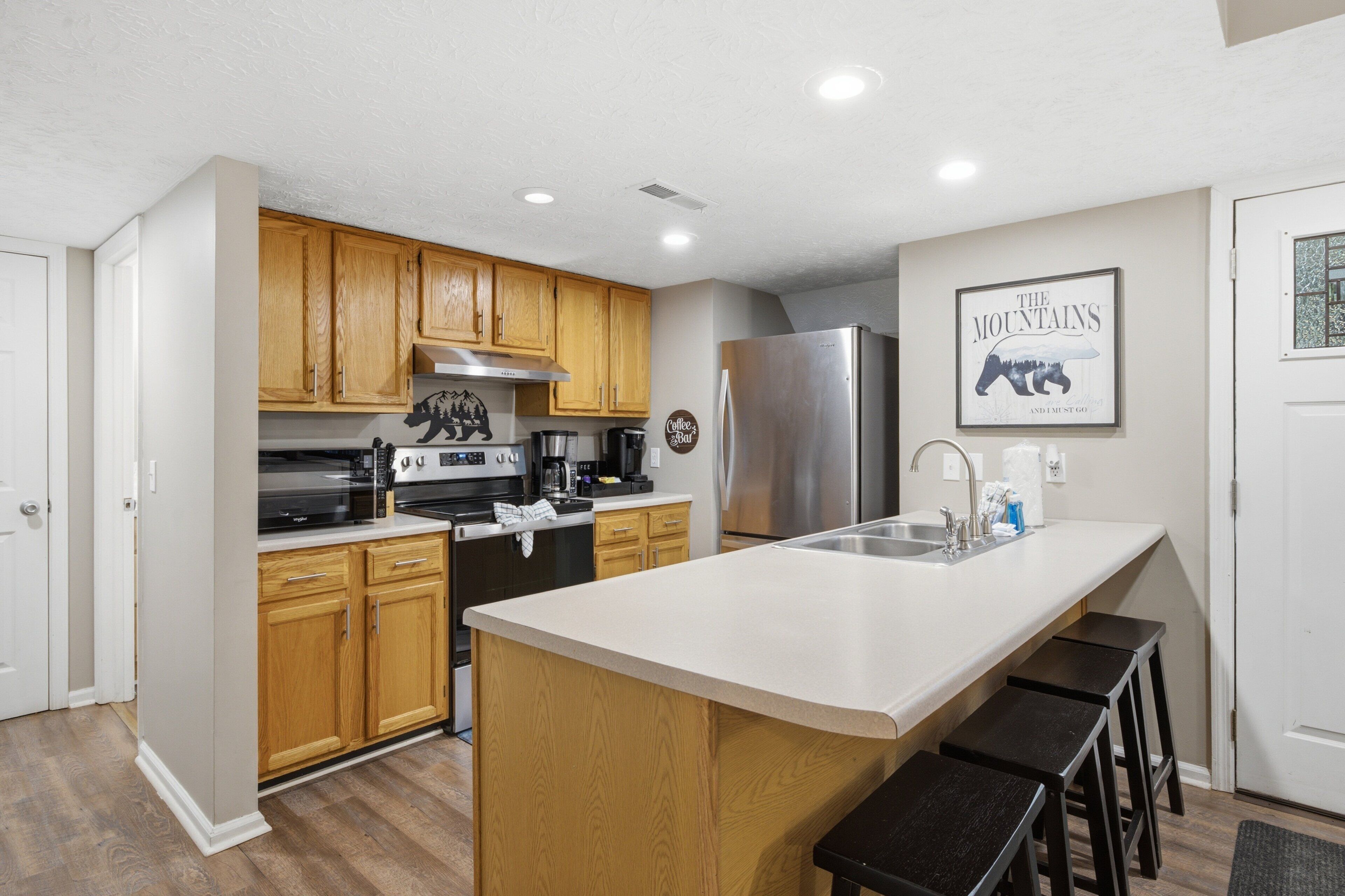 A modern kitchen with wooden cabinets, stainless steel appliances, and a large island with bar stools.
