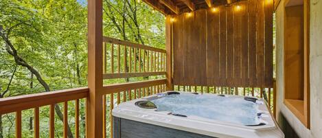 Un jacuzzi en una terraza de madera con vista a árboles.
