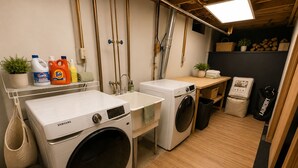 A laundry room with two washing machines, a sink, and various cleaning supplies. - Spacious Family Retreat with Several Living Areas, Backyard with Patio & Pool (Dayton)