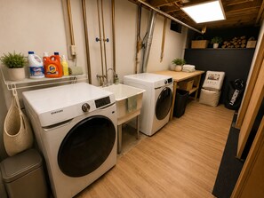 Ein Waschraum mit zwei Waschmaschinen, einem Waschbecken und verschiedenen Reinigungsmitteln.