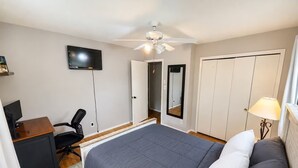 A bedroom with a bed, a desk with a chair, a television, a ceiling fan, and a wardrobe. - Spacious Family Retreat with Several Living Areas, Backyard with Patio & Pool (Dayton)