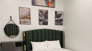 A bedroom with a bed, a desk, and three artworks on the wall.