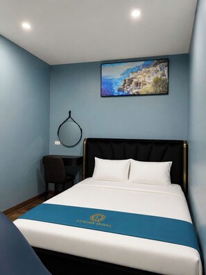 Een hotelkamer met een bed, een bureau en een schilderij aan de wand.