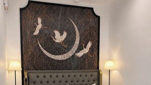 A hotel room with a large bed, a decorative wall piece, and two bedside lamps.