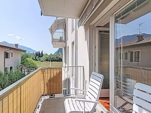 Ein Balkon mit einem weißen Stuhl, einem Holzzaun und Blick auf einen Berg sowie Gebäude.