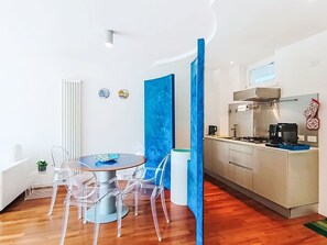 Una cucina moderna con piano cottura a gas, forno a microonde e un piccolo angolo pranzo con tavolo rotondo e sedie.