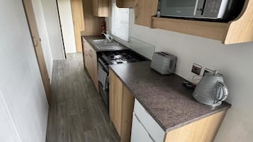 Cocina compacta equipada con microondas, tostadora, hervidor y horno pequeño.