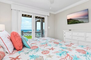 A bedroom with a bed, pillows, a dresser, a television, and a balcony with a view of the ocean. - Oceanfront Luxury 8BR w/ Pool, Hot Tub, Theater, Game Room & Elevator (Atlantic Beach)