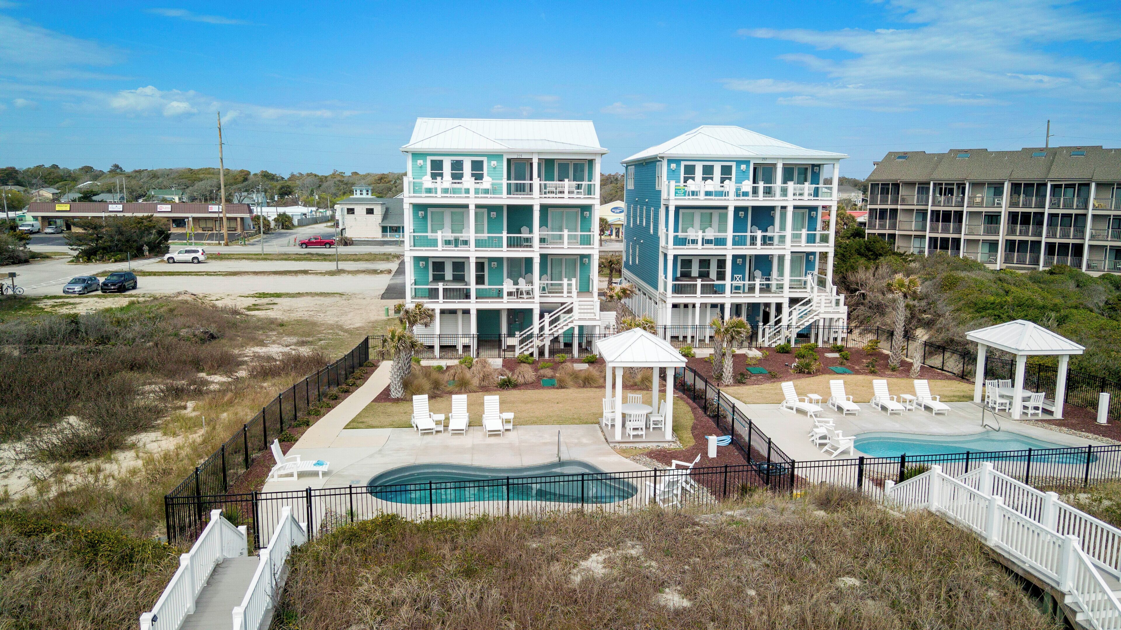 A beachfront hotel with a swimming pool, multiple balconies, and a covered patio area.