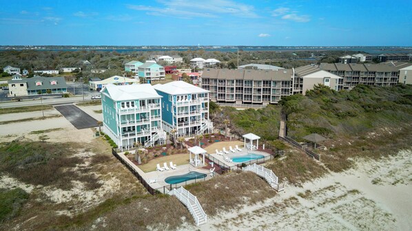 Un hôtel en bord de mer composé de plusieurs bâtiments, doté d’une piscine et d’une promenade qui mène à la plage.