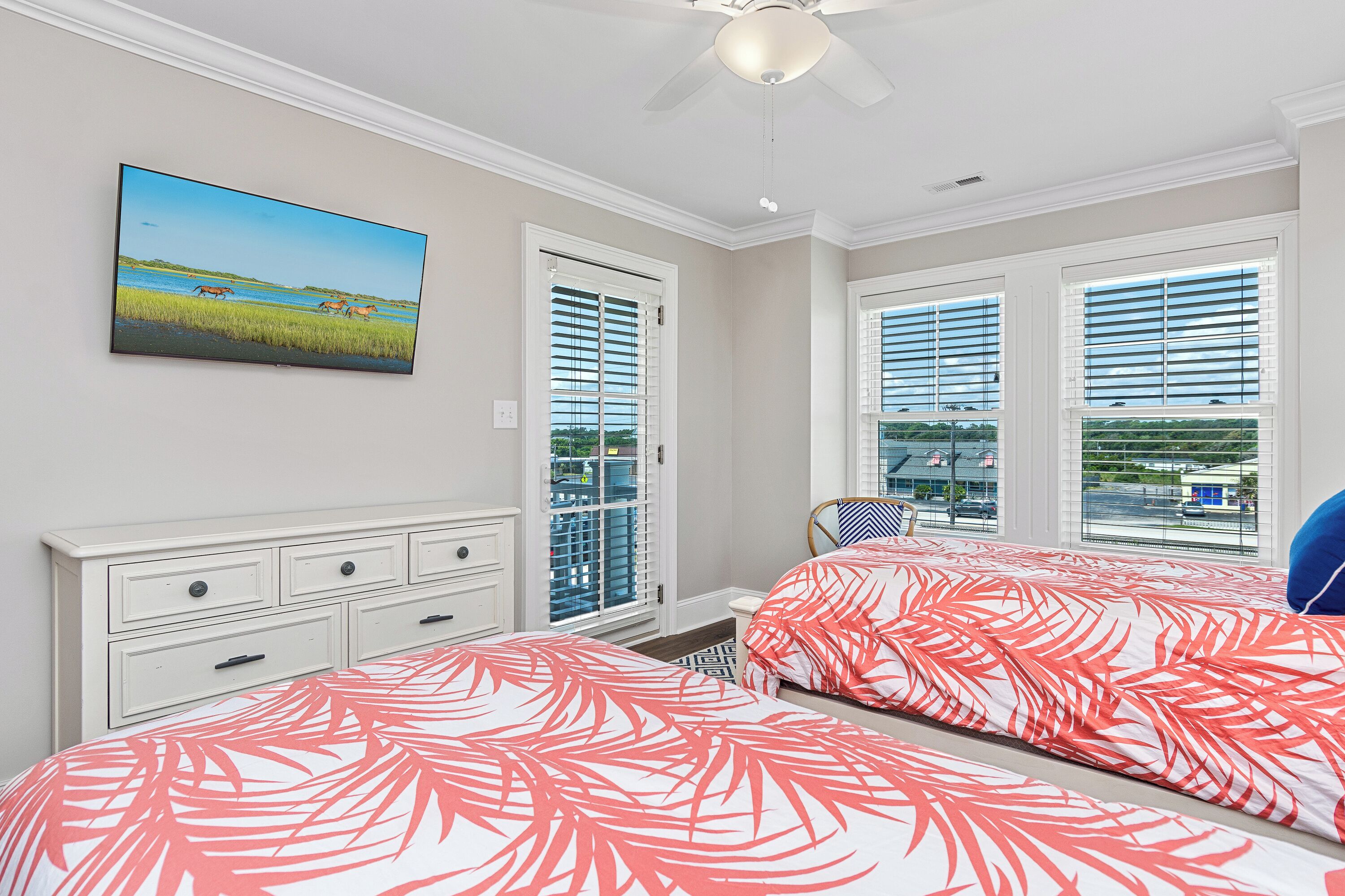 Quarto com duas camas, um ventilador de teto, um quadro e uma janela com persianas.