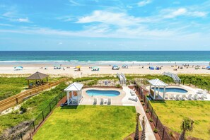 Un complexe hôtelier de bord de mer doté d’une piscine, de chaises longues et de parasols de plage.