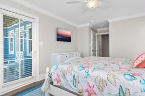 Ein Schlafzimmer mit Bett, einem Fenster mit Jalousien, einem Deckenventilator und einem an der Wand befestigten Fernseher.