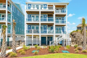 Un immeuble résidentiel à plusieurs étages, doté de balcons, d’un porche couvert et d’un jardin aménagé.
