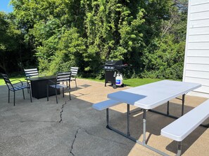 Un patio al aire libre con mesa y sillas, una parrilla y un tanque de gas.
