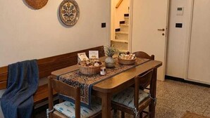 A dining area with a wooden table, chairs, and a hanging light fixture. - Charming Apartment in Vernazza IT011030C25E7RWJXG (Vernazza)